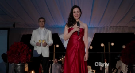 Victoria (Madeline Stowe) in a red dress, on stage.